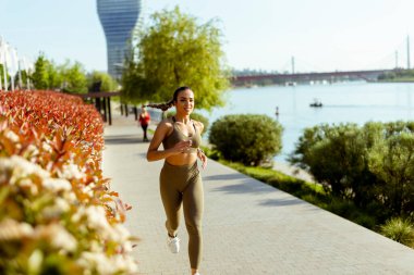 Güzel genç bayan nehir kenarında koşuya çıkıyor.