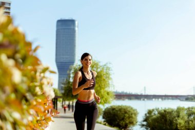 Güzel genç bayan nehir kenarında koşuya çıkıyor.