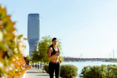 Güzel genç bayan nehir kenarında koşuya çıkıyor.