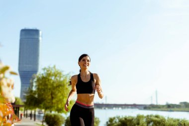 Güzel genç bayan nehir kenarında koşuya çıkıyor.