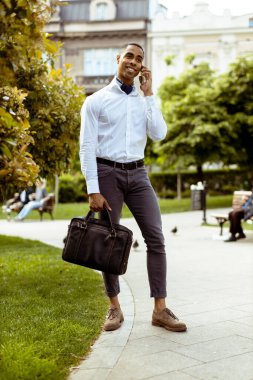 Yakışıklı Afro-Amerikan iş adamı sokakta cep telefonu kullanıyor.
