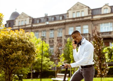 Sokakta elektrikli scooterla dururken cep telefonu kullanan yakışıklı Afrikalı genç bir Amerikalı.