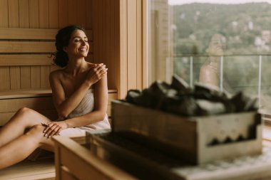 Genç ve çekici bir kadın saunada dinleniyor.