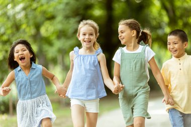 Bir grup yakışıklı Asyalı ve beyaz çocuk parkta eğleniyor.