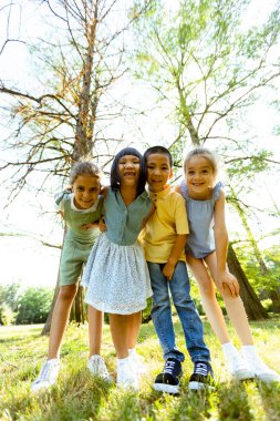 Bir grup yakışıklı Asyalı ve beyaz çocuk parkta eğleniyor.