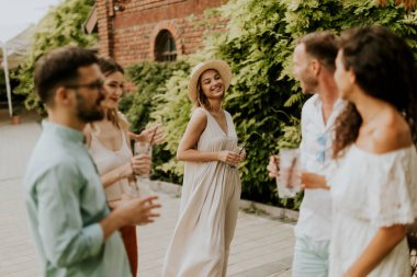 Bir grup mutlu genç dışarıda içkiyle eğleniyor ve tezahürat yapıyor.