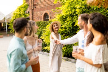 Bir grup mutlu genç dışarıda içkiyle eğleniyor ve tezahürat yapıyor.