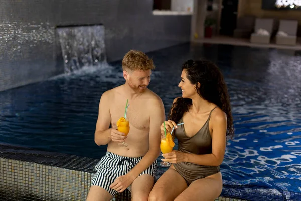 Handsome Young Couple Relaxing Drinking Fresh Orange Juice Poolside — Foto de Stock