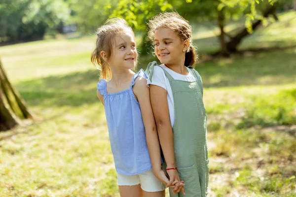 Δύο Χαριτωμένα Κοριτσάκια Στέκονται Πλάτη Πλάτη Στο Πάρκο — Φωτογραφία Αρχείου