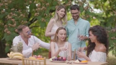 Taze limonatayla tezahürat yapan ve bahçede meyve yiyen bir grup mutlu genç.