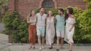 Bir grup mutlu genç dışarıda eğleniyor.