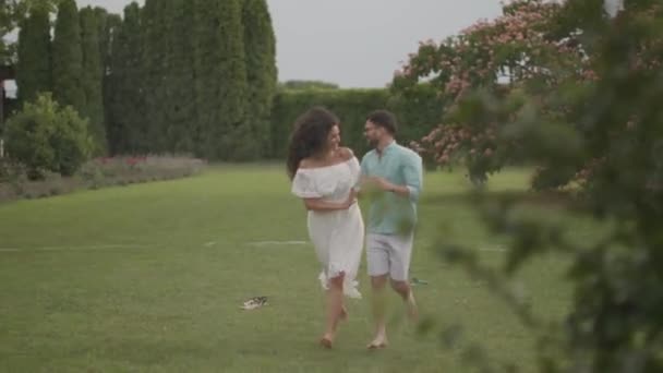 一对快乐的年轻夫妇被公园里突如其来的洒水水给困住了 — 图库视频影像