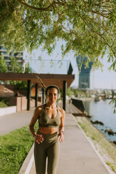 在沿河长廊上奔跑的活跃的年轻美女的全景 — 图库照片