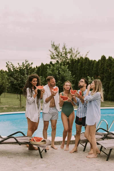 Group Young People Standing Swimming Pool Eating Watermellon House Backyard — Stockfoto