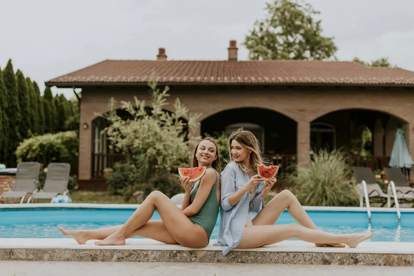 Two Cute Young Women Sitting Swimming Pool Eating Watermelon House — Stockfoto