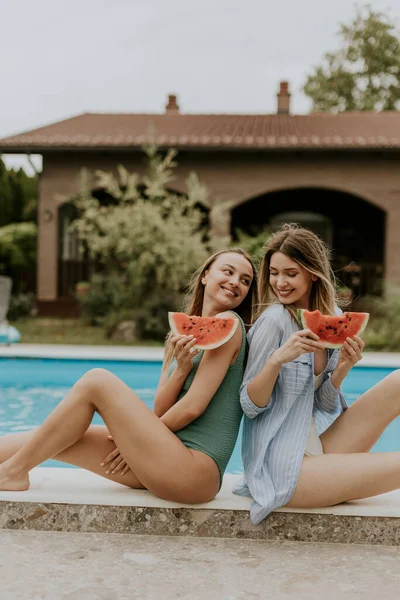 Two Cute Young Women Sitting Swimming Pool Eating Watermelon House — Stockfoto