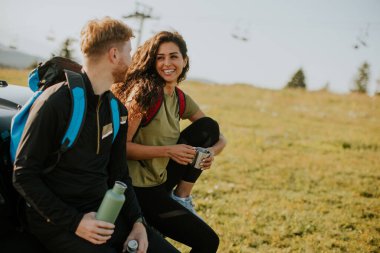 Yakışıklı genç çift kırsal kesimde arazi aracı kaputunda dinleniyor.