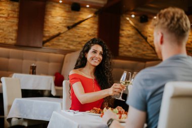 Yakışıklı genç çift restoranda beyaz şarapla yemek yiyor.