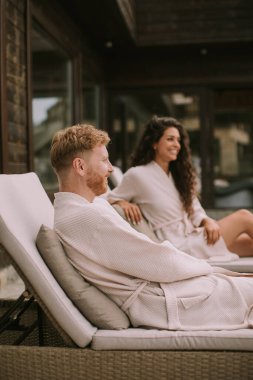 Handsome young couple relaxing on beds on the outdoor terrace