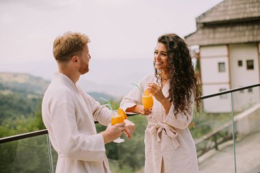 Handsome young  relaxing on  the outdoor terrace and drinking fresh orange juice