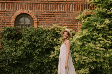 Otelin bahçesinde yürüyen şapkalı güzel bir kadın.