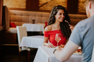 Yakışıklı genç çift restoranda beyaz şarapla yemek yiyor.