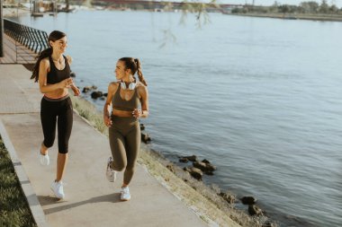 Güzel genç bayan nehir kenarında koşuya çıkıyor.