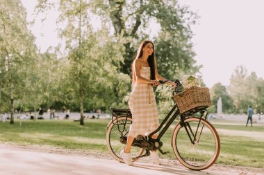 Elektrikli bisikleti ve sepetinde çiçekleri olan güzel bir kadın.