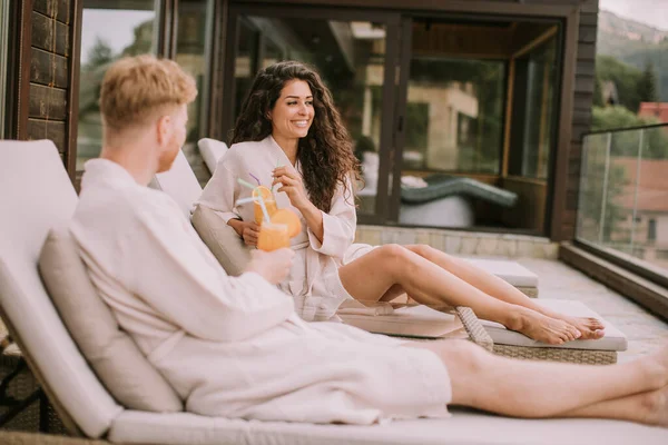 Yakışıklı genç çift yataklarında dinleniyor ve terasta taze portakal suyu içiyor.