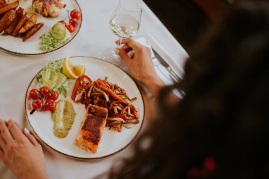 Yakışıklı genç çift restoranda beyaz şarapla yemek yiyor.