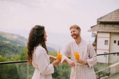 Handsome young  relaxing on  the outdoor terrace and drinking fresh orange juice