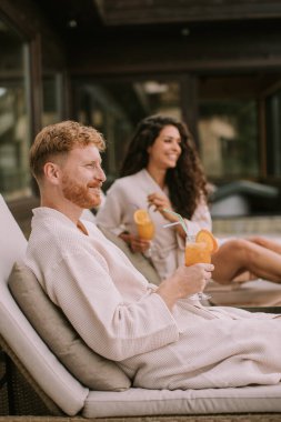 Yakışıklı genç çift yataklarında dinleniyor ve terasta taze portakal suyu içiyor.