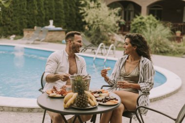 Handsome young couple sitting in the backyard, drinking lemande and eating fresh fruits