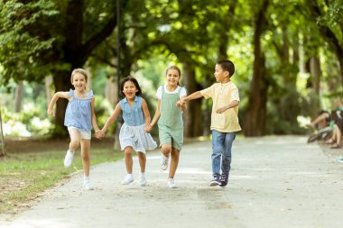 Group of cute asian and caucasian kids having fun in the park