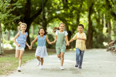 Group of cute asian and caucasian kids having fun in the park