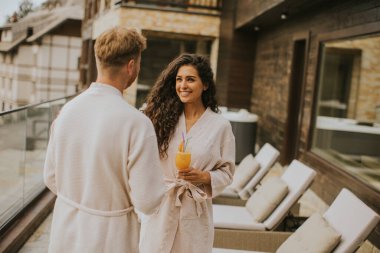 Handsome young  relaxing on the outdoor terrace and drinking fresh orange juice