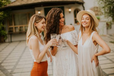 Bir grup mutlu genç dışarıda taze limonatayla tezahürat yapıyor ve eğleniyor.