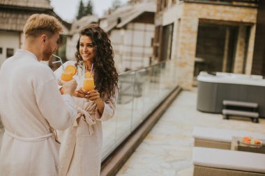 Handsome young  relaxing on the outdoor terrace and drinking fresh orange juice
