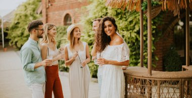 Bir grup mutlu genç dışarıda içkiyle eğleniyor ve tezahürat yapıyor.