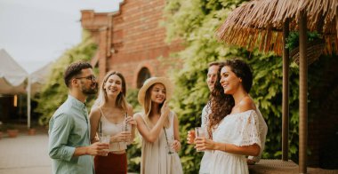 Bir grup mutlu genç dışarıda içkiyle eğleniyor ve tezahürat yapıyor.