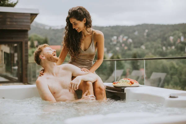 Attractive young couple enjoying in outdoor hot tub on vacation