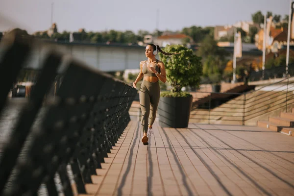 在沿河长廊上奔跑的活跃的年轻美女的全景 — 图库照片