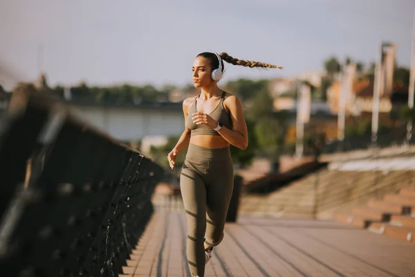 在沿河长廊上奔跑的活跃的年轻美女的全景 — 图库照片