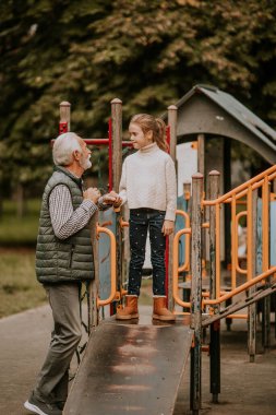 Yakışıklı büyükbaba sonbahar günü torunuyla parkta vakit geçiriyor.