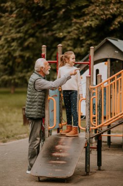 Yakışıklı büyükbaba, sonbahar günü torunuyla parkta vakit geçiriyor.