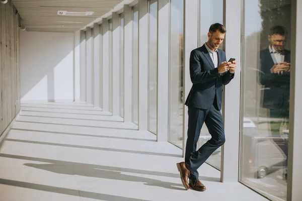 Красивий Молодий Бізнесмен Використовуючи Мобільний Телефон Сучасному Офісному Коридорі — стокове фото