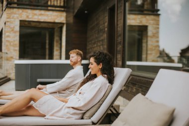 Handsome young couple relaxing on beds on the outdoor terrace