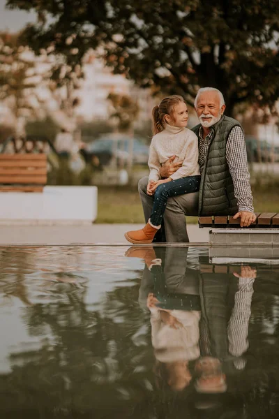 秋の日に孫と一緒に公園の小さなプールで過ごすハンサムな祖父 — ストック写真