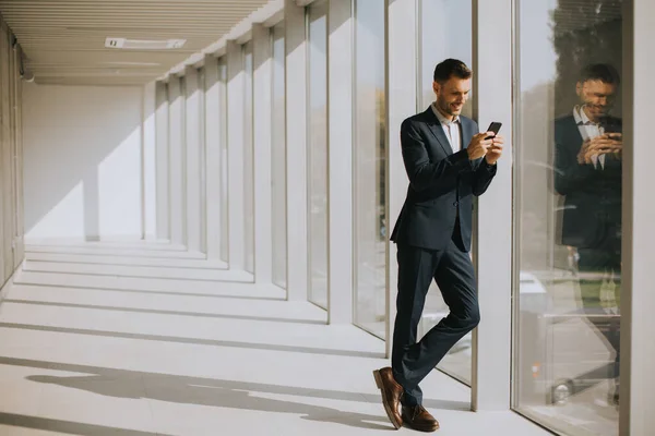 Красивый Молодой Бизнесмен Использующий Мобильный Телефон Современном Офисном Коридоре — стоковое фото