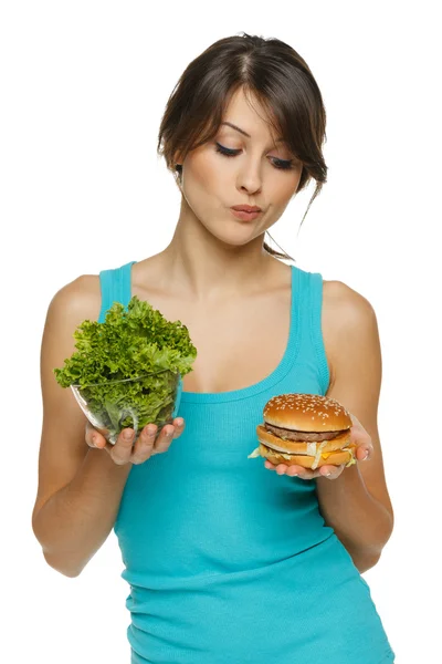 Vrouw overgaat tussen gezonde salade en fast food Rechtenvrije Stockfoto's